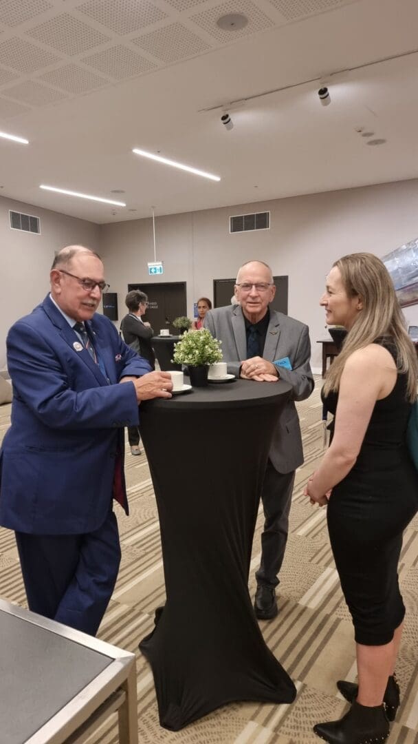 Two older male doctors gray hair standing coffee cups speaking female doctor blond hair OUM