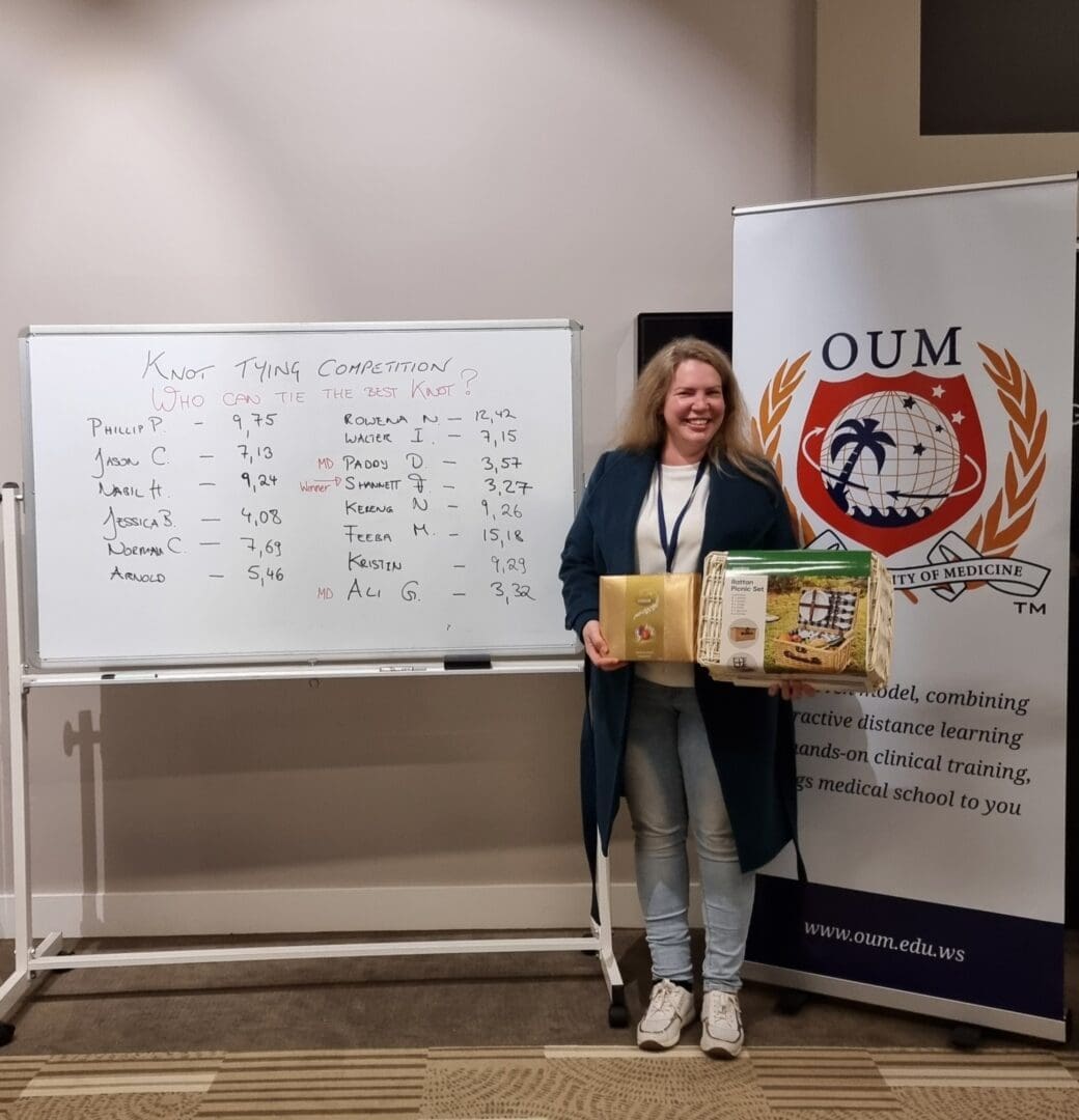 White board left OUM banner right happy women middle holding gifts long hair navy sweater