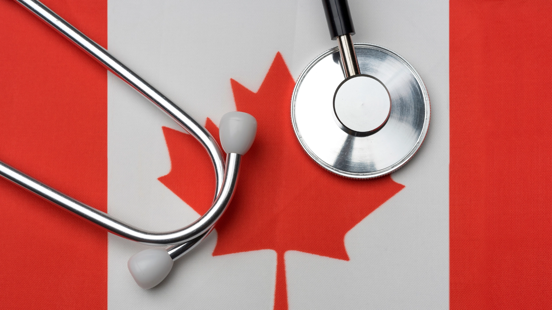 A stethoscope placed on top of a Canadian flag, symbolizing healthcare and the medical profession in Canada