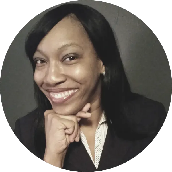 headshot of smiling black doctor with long black hair, fist on ching, and wearing a dark jacket