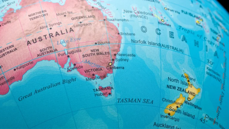 Close-up of a globe showing Australia, New Zealand, and surrounding regions, with major cities and geographic features labeled