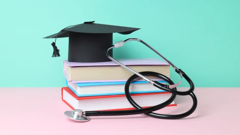 Stack of colorful books with a graduation cap on top and a stethoscope draped over them, symbolizing medical education and academic achievement