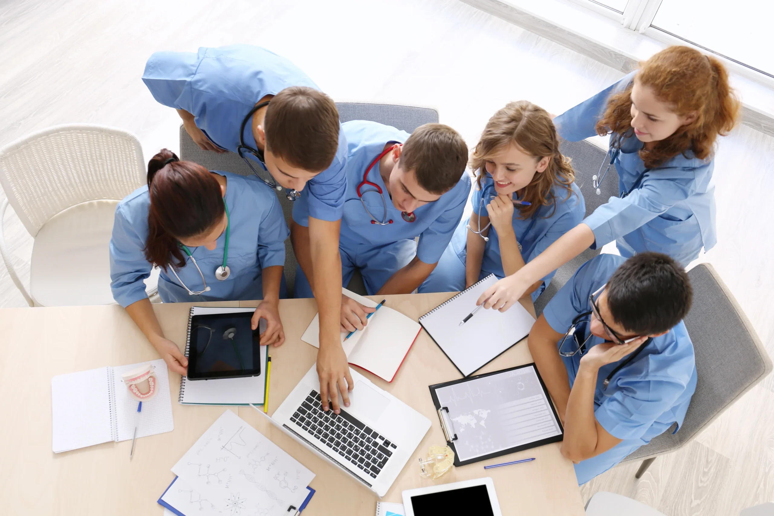 Medical Students at Desk Studying on Laptop and with Notepads