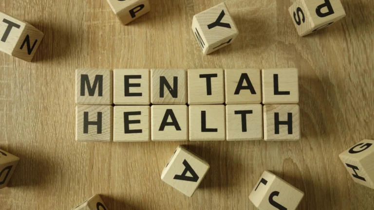 Wooden letter blocks spelling out “Mental Health” on a wooden table, symbolizing awareness and discussion around mental health and wellness