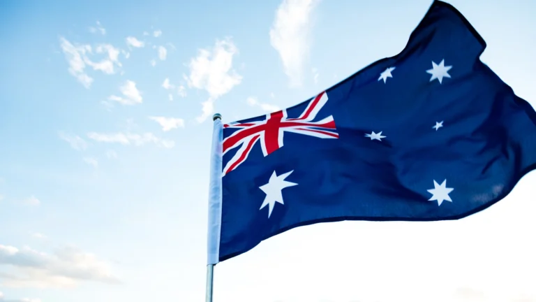 Australian national flag waving against a bright blue sky with scattered clouds