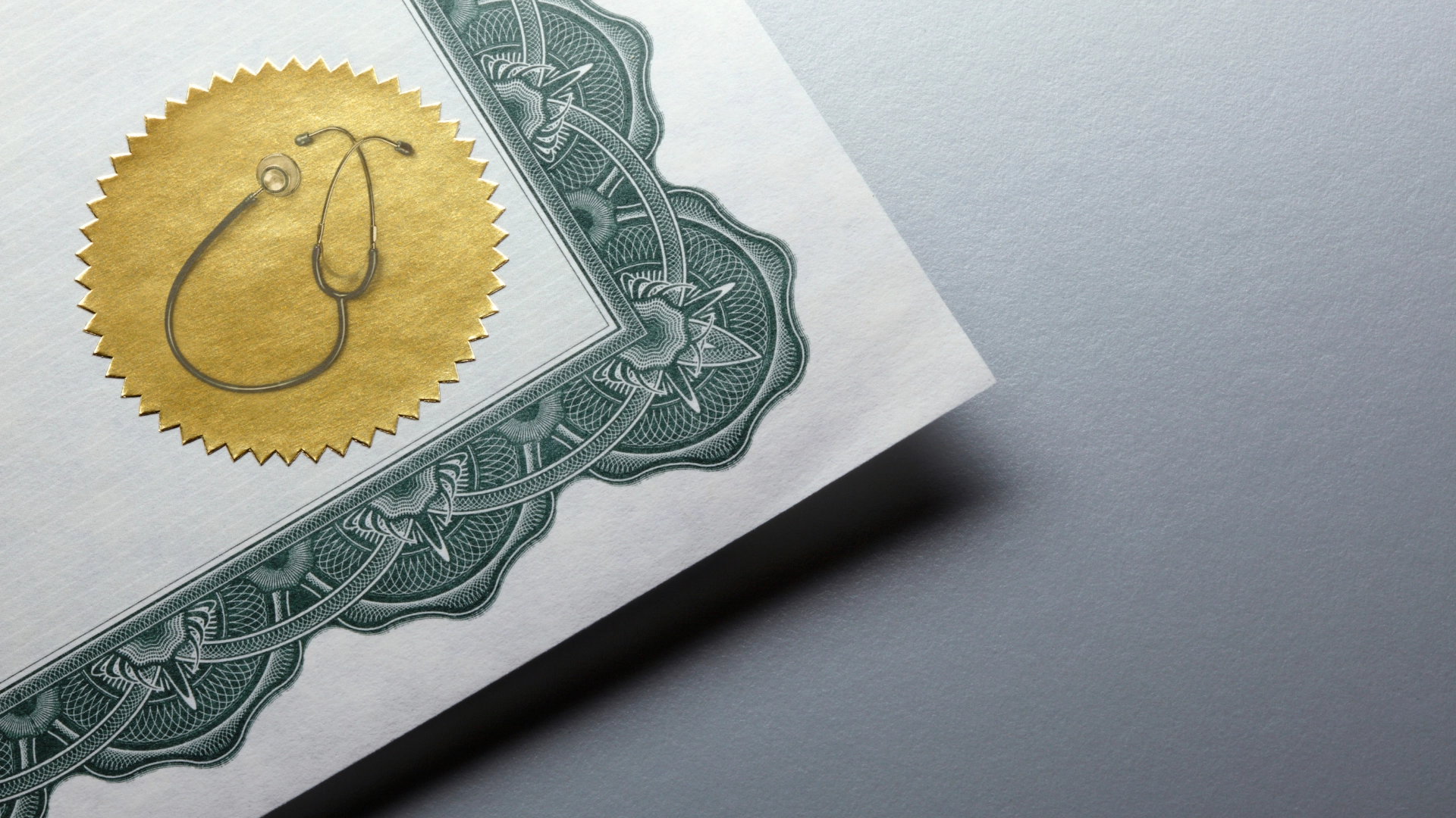 Close-up of a medical certificate with a gold seal featuring a stethoscope and an ornate green border