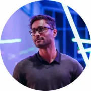 Profile picture of a person with dark hair, glasses, dark gray polo shirt and looking to the side.