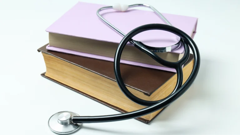 Stack of medical textbooks with a stethoscope draped over them, symbolizing the connection between education and medical practice