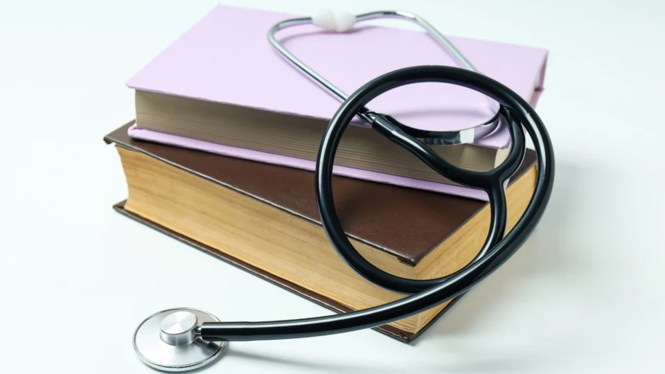 Stack of medical textbooks with a stethoscope draped over them, symbolizing the connection between education and medical practice