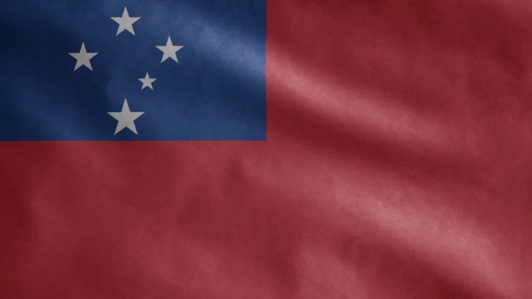 Waving national flag of Samoa featuring a blue rectangle with white stars in the upper left corner and a red background