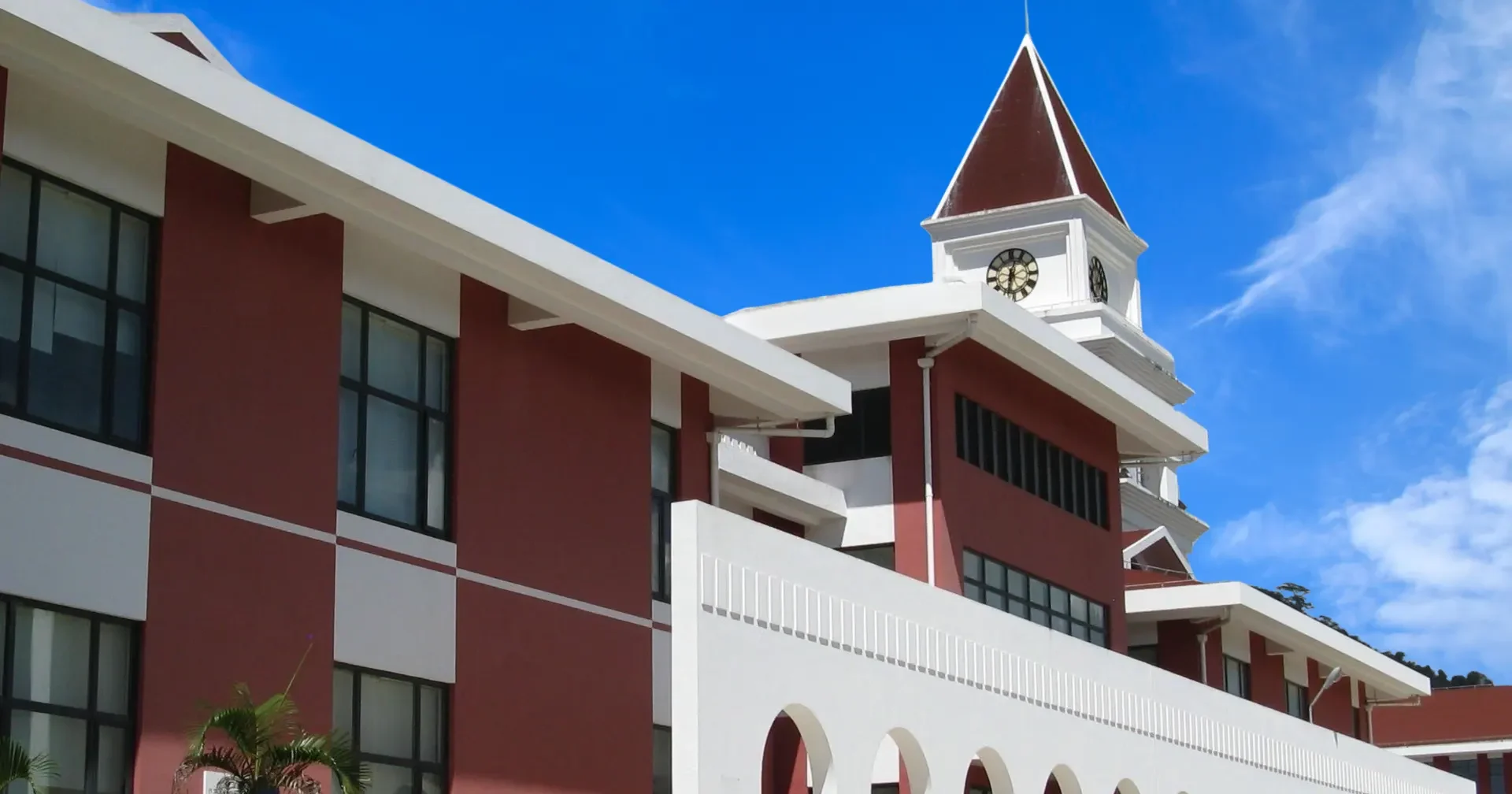 red brick and white hospital building with a white wall with many arched opening and nurse walking by dressed in white