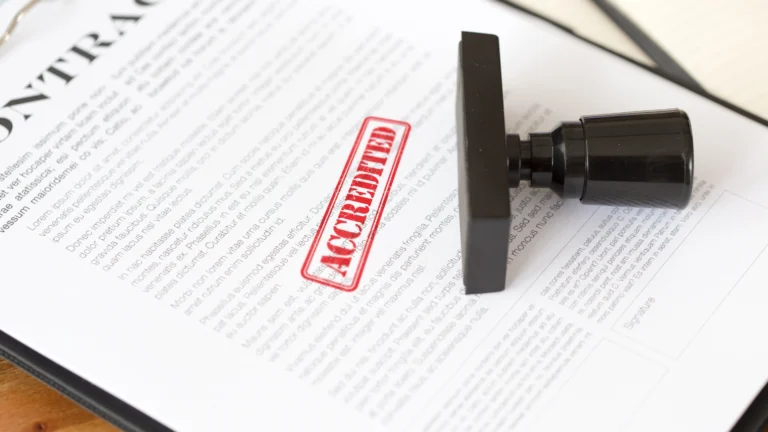 Close-up of a contract document stamped with a bold red “ACCREDITED” mark, with the stamp lying on top of the paper