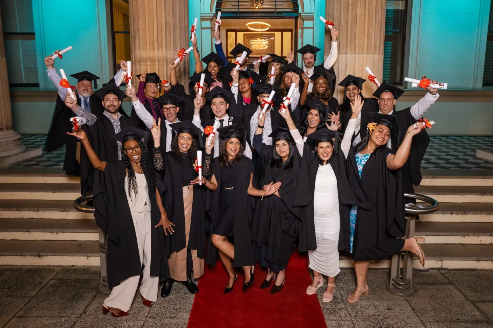diverse group of graduating doctors in black cap and gown waving their diplomas