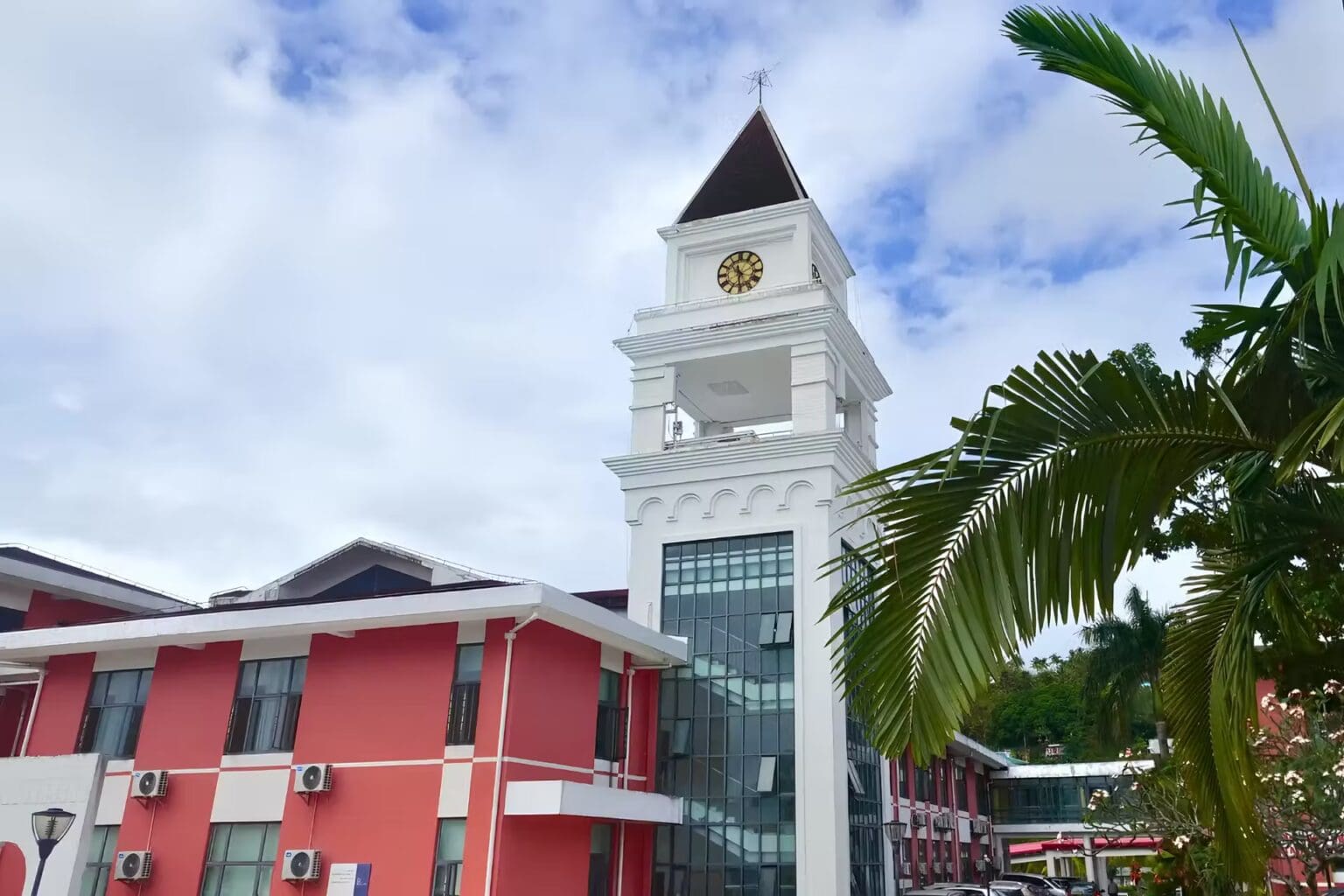 red brick and white hospital building with a clock tower with floor to ceiling windows