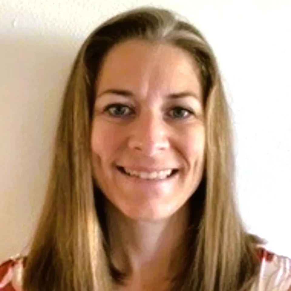 Professional headshot of a smiling woman with long blonde hair wearing a light-colored top.