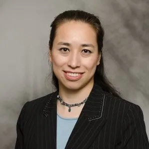 A portrait of a smiling woman with short dark hair, wearing a dark stripped suit.